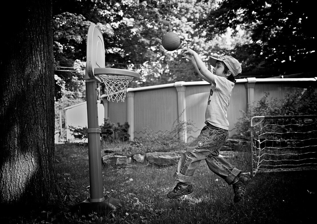 Boy playing in yard with a toy basketball set, Otterburn park, Quebec