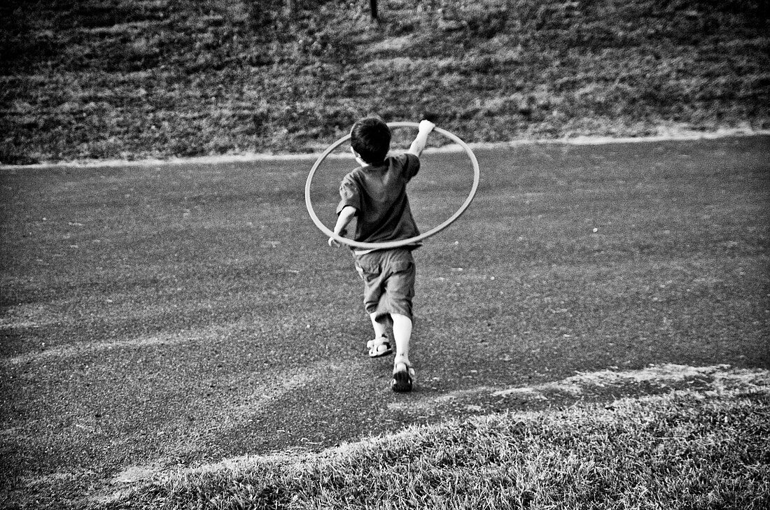 Young boy running with hula hoop, Otterburn Park, Quebec