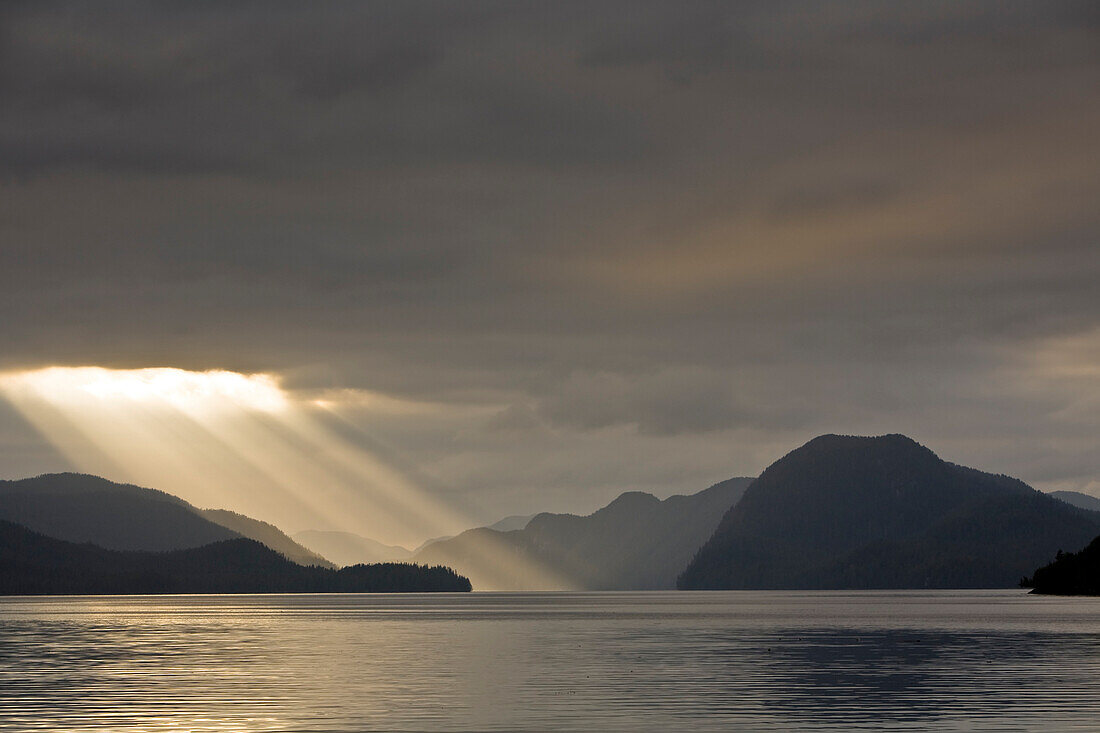 Sunrays stream out of the clouds in Oscar Channel, Salmon Bay, Great Bear Rainforest, British Columbia