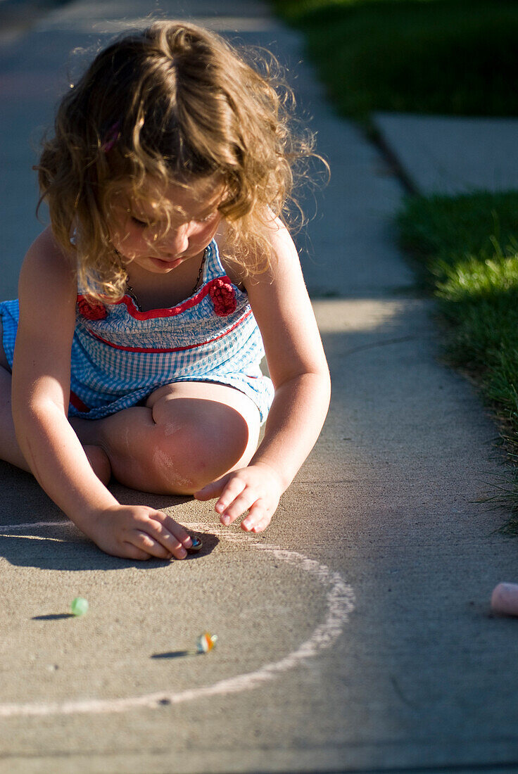 Young girl playing with marbles on the sidewalk, Regina, Saskatchewan
