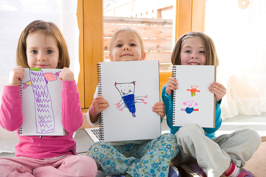 Three little girls holding artwork, Toronto, Ontario