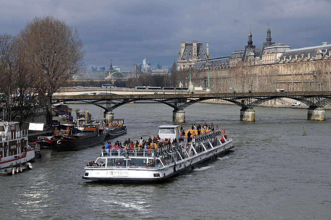 Excursion boat on the river Seine at Ile de la Cite with view towards the Louvre and La Defense, Paris, France