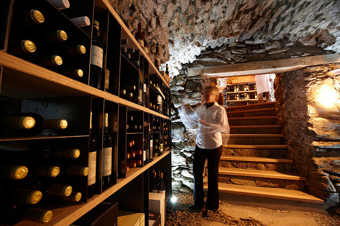 Frau nimmt Wein aus Regal in einem Weinkeller, Karthaus, Schnalstal, Südtirol, Alto Adige, Italien