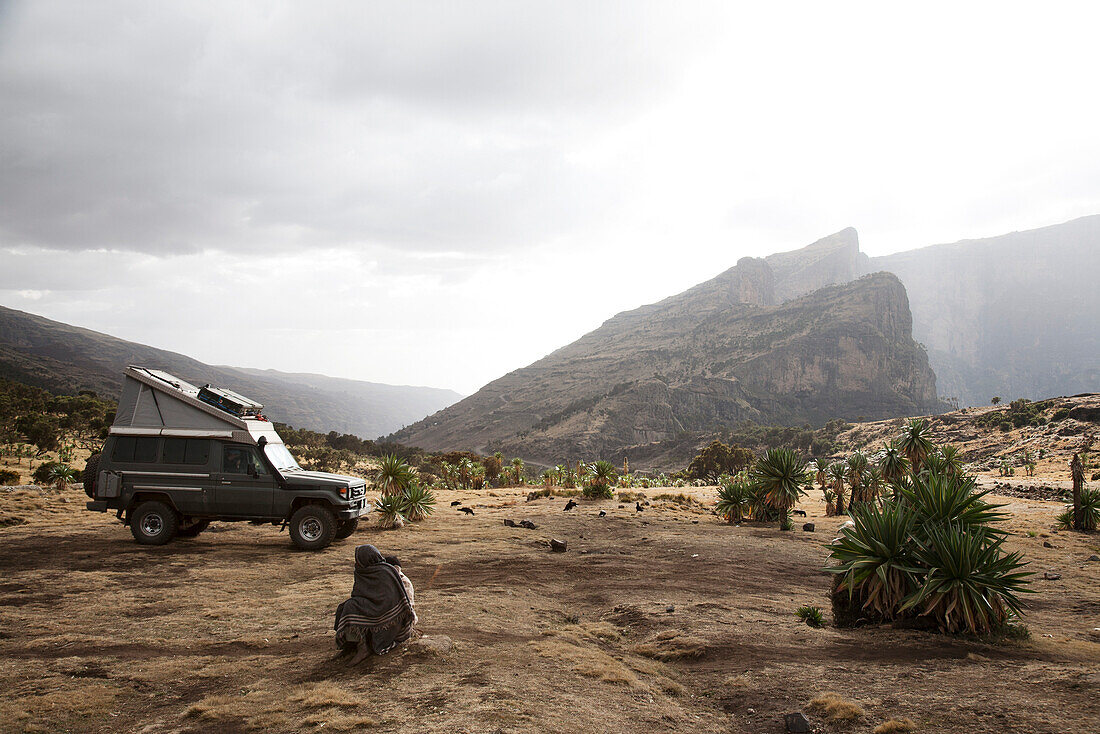 Children sitting on ground near a off-road vehicle, mountains in backgorund, Simien Mountains National Park, Ethiopia