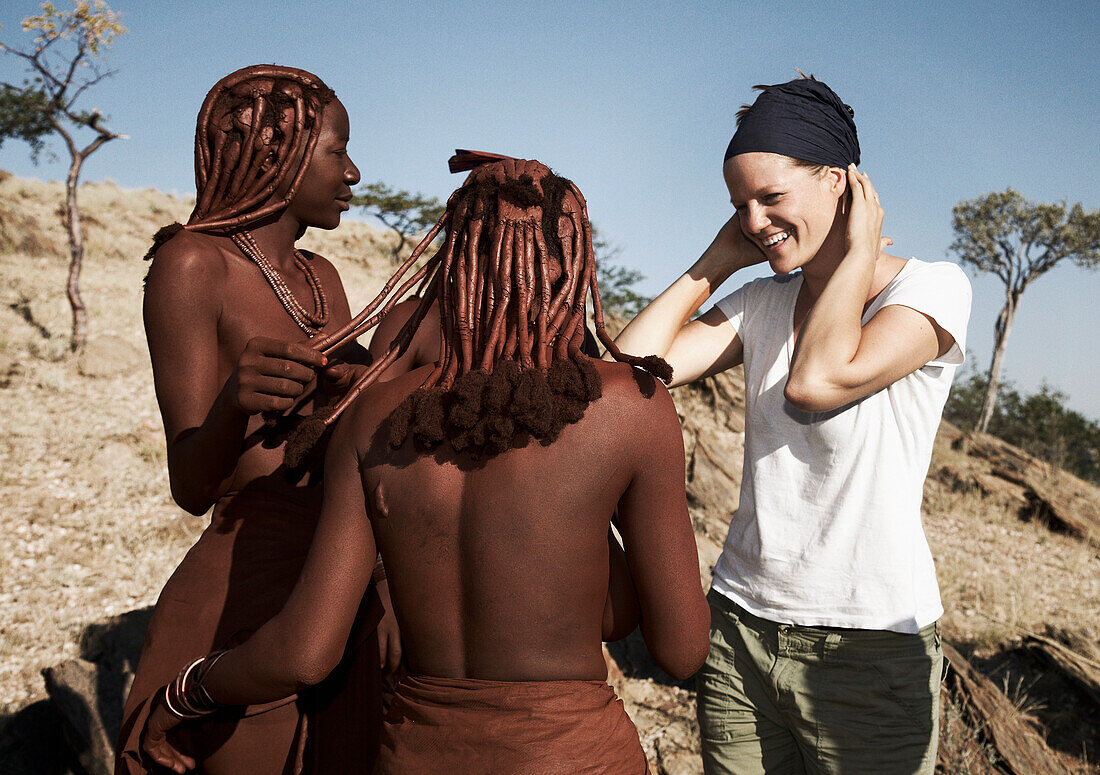 Himba women and a female tourist, Hartmann valley, Kaokoveld, Kunene region, Namibia