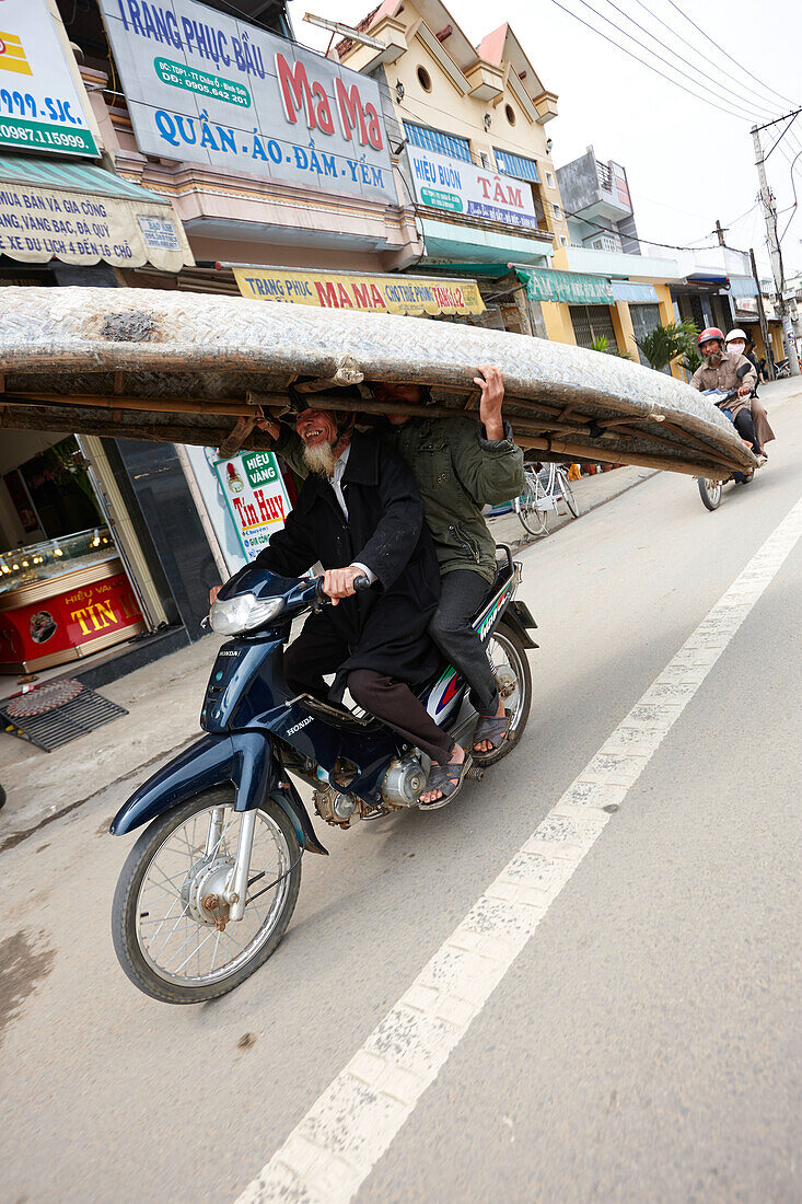 Männer transportieren geflochtenes altes Boot auf einem Moped, Quang Ngai, Vietnam