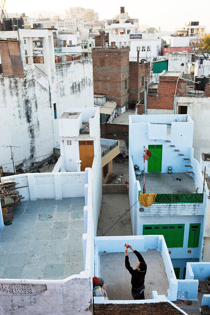 Blick auf Dachterassen und gläubigen Hindu beim morgentlichen Ritual, Udaipur, Rajasthan, Indien