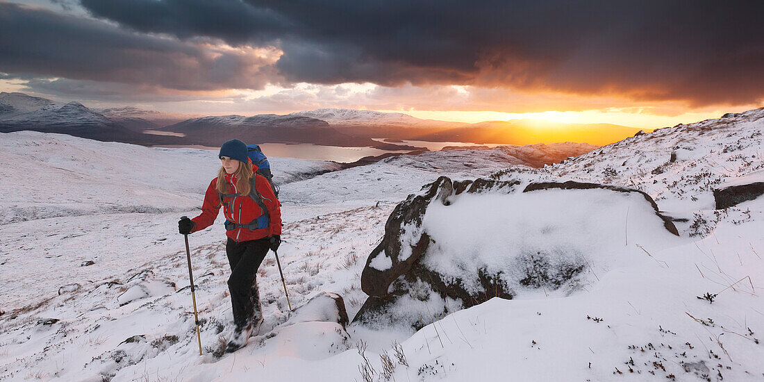 Junge Frau wandert über verschneite Northwest Highlands, Torridon, Schottland, Großbritannien
