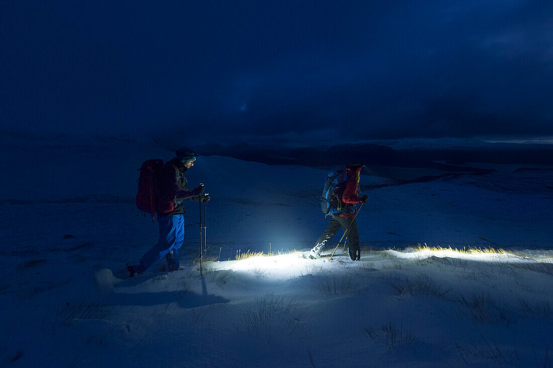Junges Paar wandert über verschneite Highlands, Wester Ross, Torridon, Schottland, Großbritannien