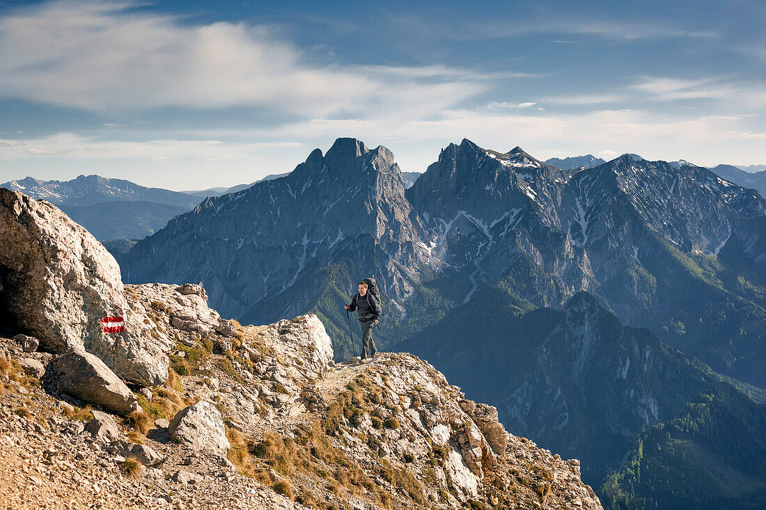 Junger Mann mit Rucksack wandert auf einem steilen Bergpfad am Großen Buchstein, Nationalpark Gesäuse, Admonter Reichensteingruppe im Hintergrund, Ennstaler Alpen, Steiermark, Österreich