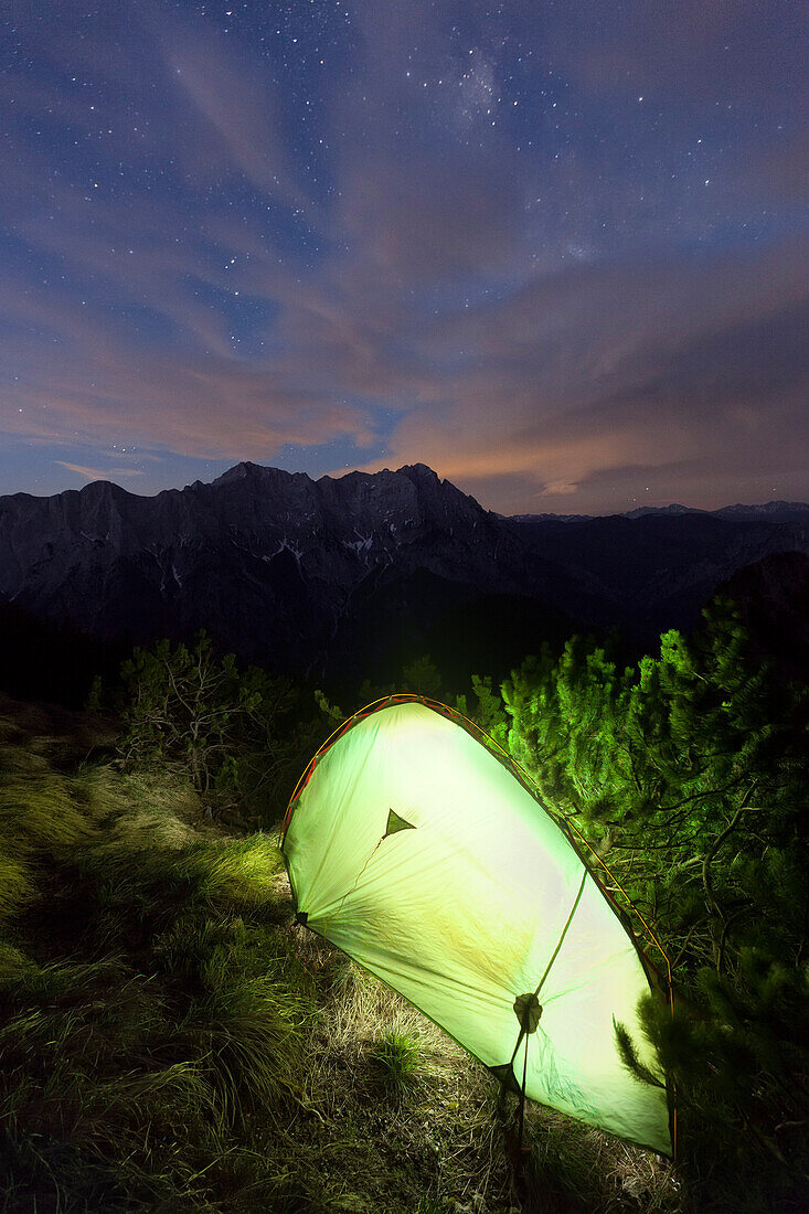 lluminated tent, Hochtor mountain range in background, Gesause National Park, Ennstal Alps, Styria, Austria