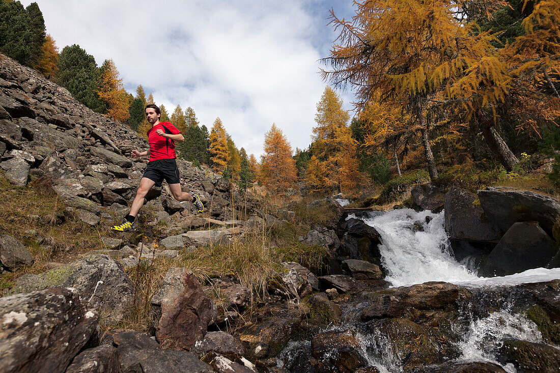 Junger Mann läuft auf einem steinigen Wanderweg, Zaytal, Nationalpark Stilfser Joch, Südtirol, Italien