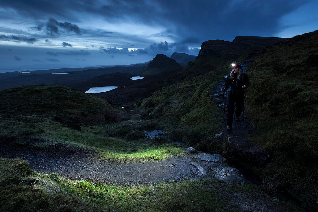 Junge Frau mit Stirnlampe wandert in der Dämmerung, Quiraing, Trotternish Halbinsel, Isle of Skye, Schottland, Großbritannien