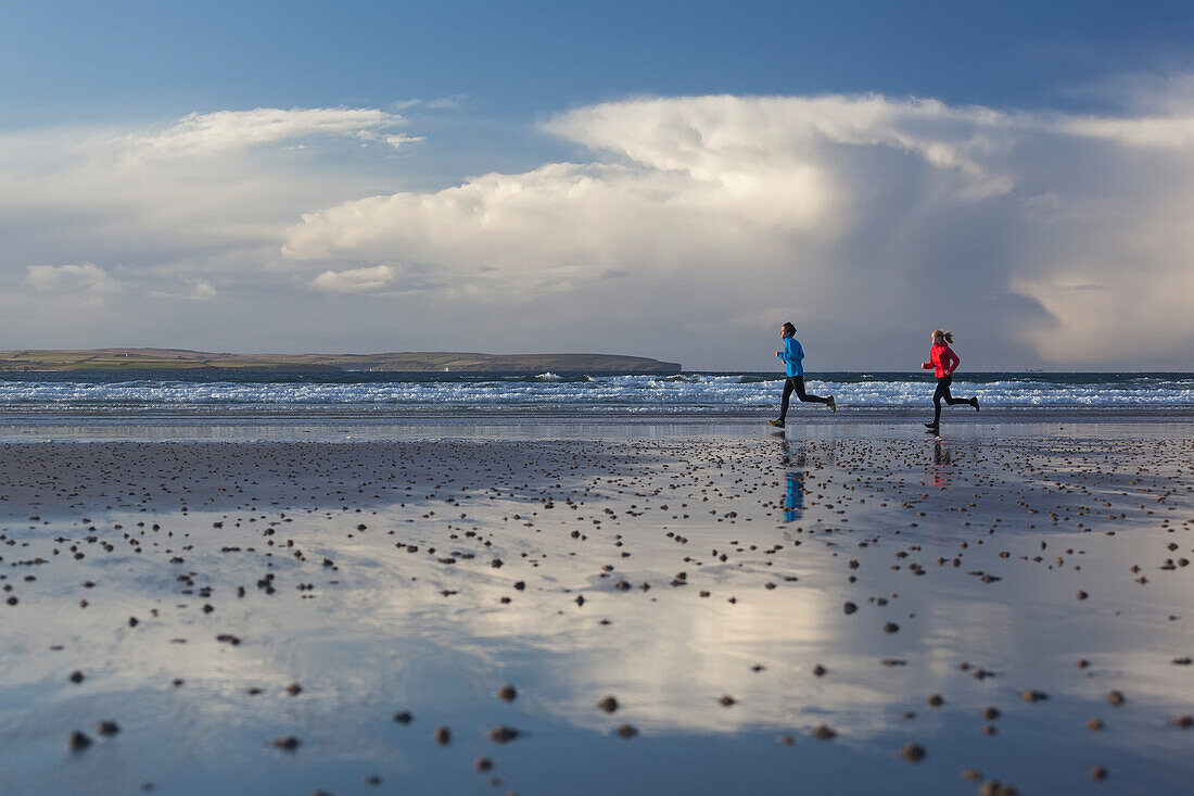 Junges Paar joggt am Strand, Dunnet Bay, Caithness, Schottland, Großbritannien