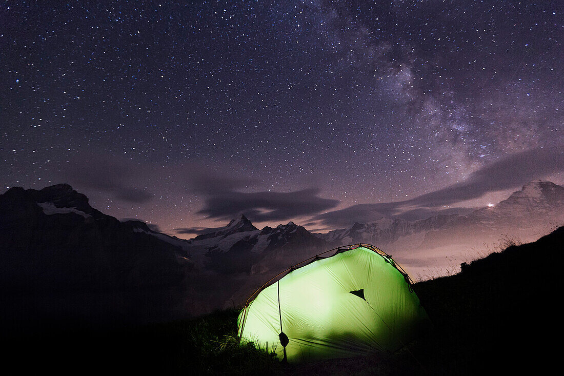 Beleuchtetes Zelt unter Sternenhimmel, Schreckhorn, Finsteraarhorn und Eiger im Hintergrund, Grindelwald, Berner Oberland, Schweiz