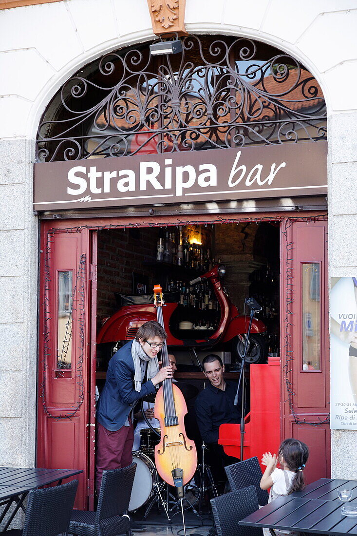 Child applauding musicians in a bar, Milan, Lombardy, Italy
