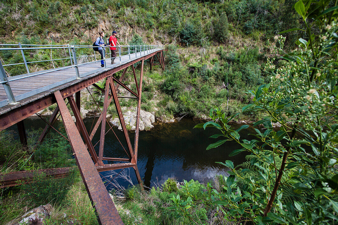 Couple standing on an old railway bridge over the Thomson River, Walhalla, Victoria, Australia