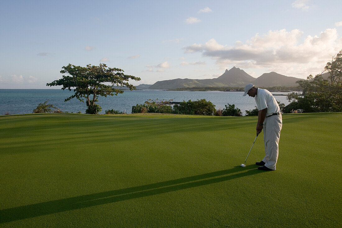 Ein Golfspieler auf dem Grün von Loch 11 Round the Bend auf dem Le Touessrok Golf Course, nahe Trou d'Eau Douce, Flacq District, Mauritius, Indischer Ozean