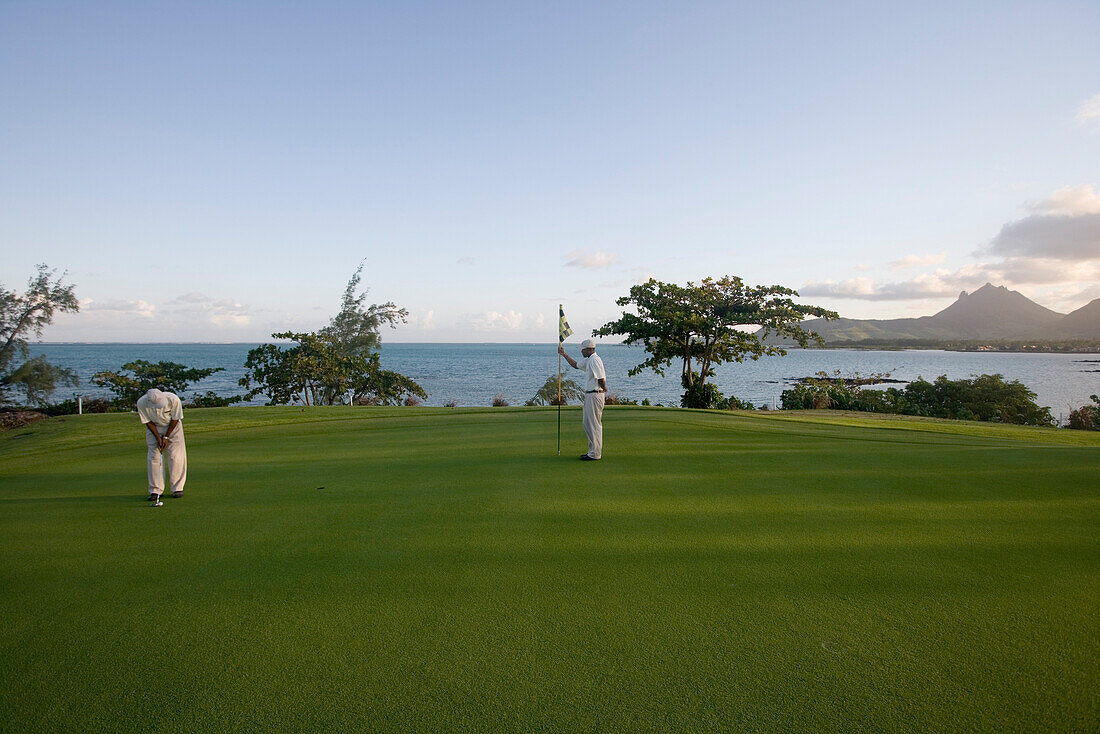 Zwei Golfspieler auf dem Grün von Loch 11 Round the Bend auf dem Le Touessrok Golf Course, nahe Trou d'Eau Douce, Flacq District, Mauritius, Indischer Ozean