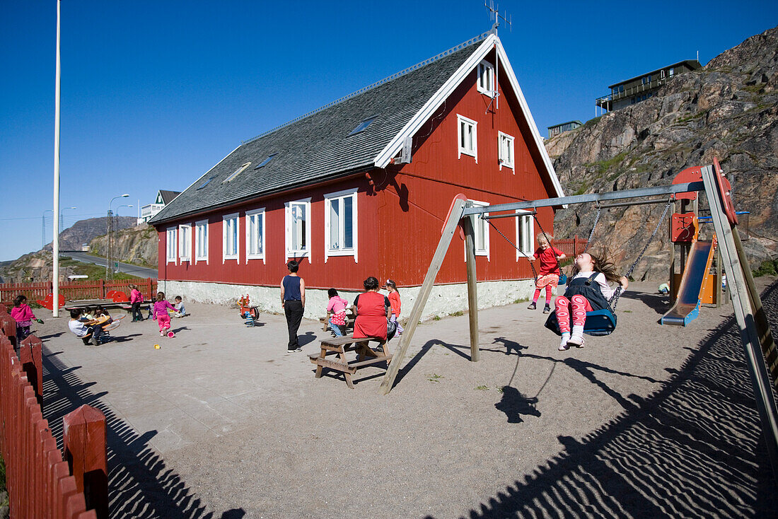 Kinder spielen und schaukeln auf dem Hof von Kindergarten, Sisimiut (Holsteinsborg), Kitaa, Grönland, Europa