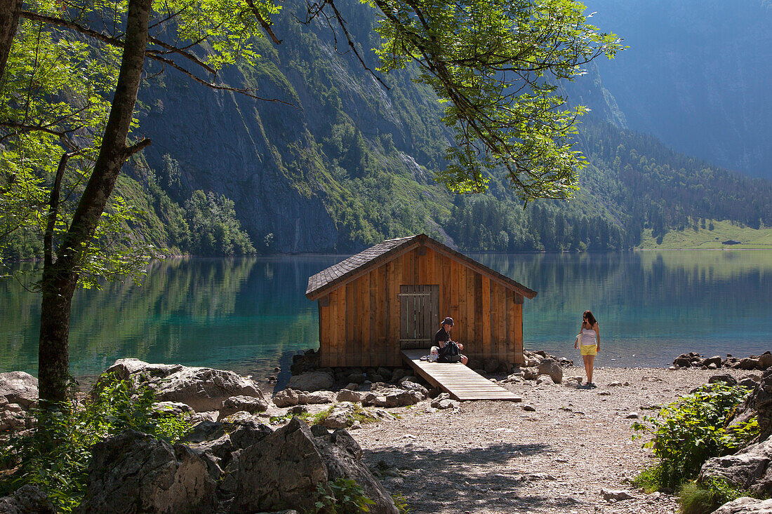 Young couple having a rest at a boat house at Obersee, Koenigssee, Berchtesgaden region, Berchtesgaden National Park, Upper Bavaria, Germany