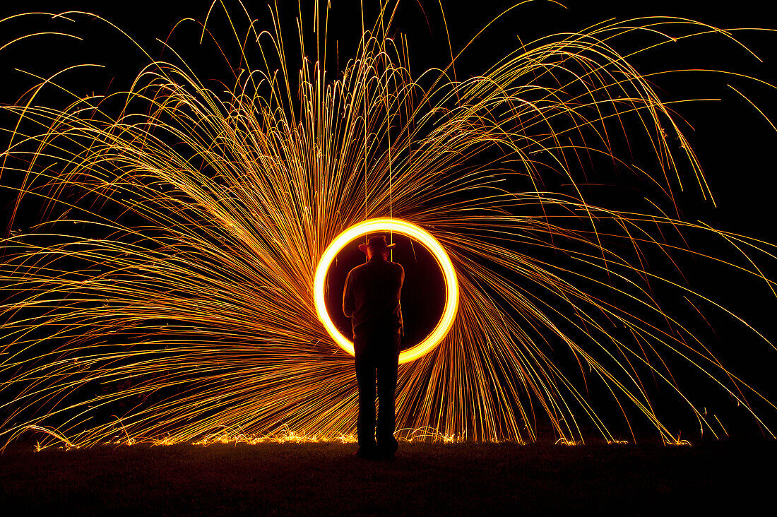 Man Spinning Ball Of Burning Steel Wool At Night, Petersfield, Hampshire, Uk