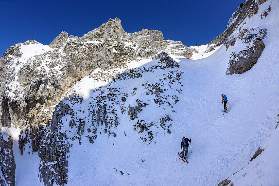 Two female backcountry skiers ascending through bold cirque to Monte Pesco Falcone, Rava del Ferro, Maiella, Abruzzo, Italy