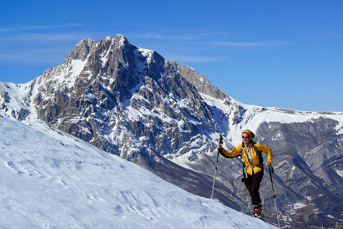 Skitourengeherin steigt zum Monte Prena auf, Gran Sasso im Hintergrund, Abruzzen, Italien