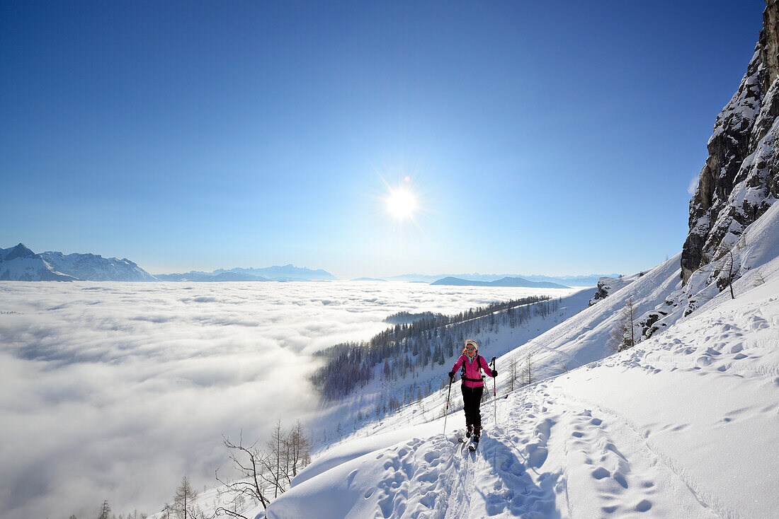 Female backcountry skier ascending to Hochkoenig, sea of fog in the valley of Salzach, Berchtesgaden Alps, Salzburg, Austria