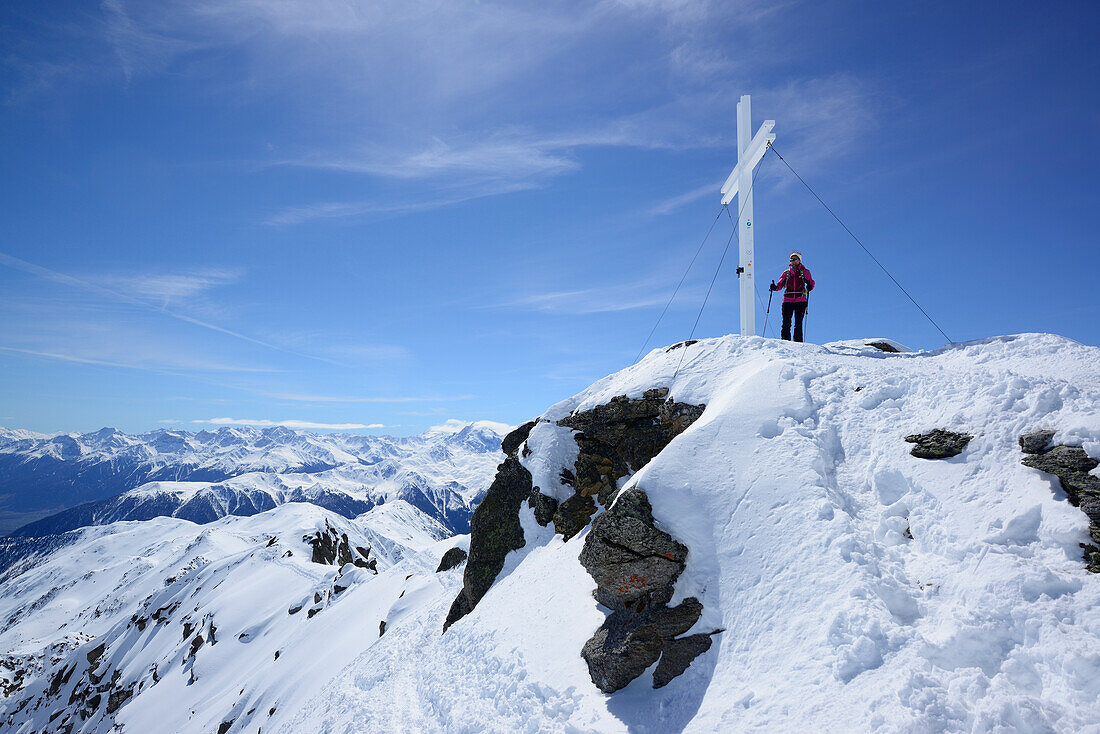 Frau steht am Gipfelkreuz des Piz Sesvenna, Sesvennagruppe, Engadin, Graubünden, Schweiz