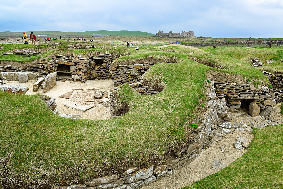Personen besichtigen die steinzeitliche Siedlung Skara Brae, Skara Brae, UNESCO Weltkulturerbe The Heart of Neolithic Orkney, Orkney Inseln, Schottland, Großbritannien, Vereinigtes Königreich