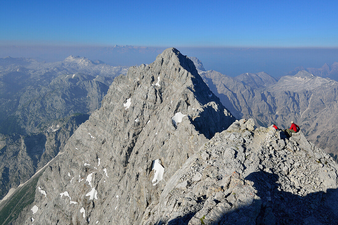 Man sitting on ridge and looking towards Suedspitze of Watzmann, at Mittelspitze of Watzmann, Steinernes Meer in the background, Watzmann, crossing over of Watzmann, Berchtesgaden range, National Park Berchtesgaden, Berchtesgaden, Upper Bavaria, Bavaria, 