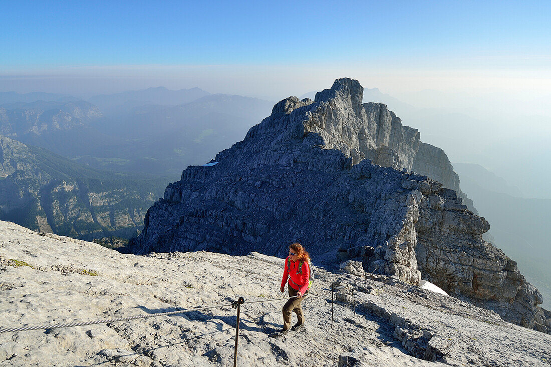Woman ascending alongside fixed ropes to Watzmann, Hocheck in background, Berchtesgaden Alps, Berchtesgaden National Park, Berchtesgaden, Upper Bavaria, Bavaria, Germany