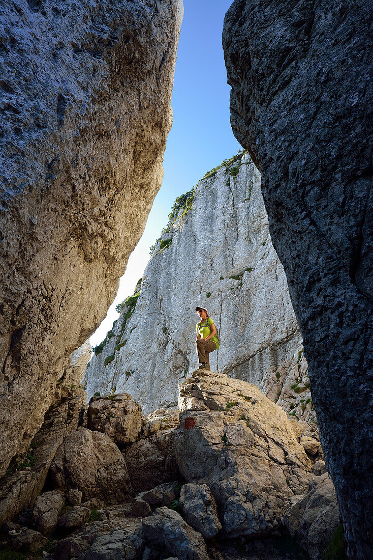 Woman standing on boulder in canyon Kaisersaele, Kampenwand, Chiemgau Alps, Chiemgau, Upper Bavaria, Bavaria, Germany