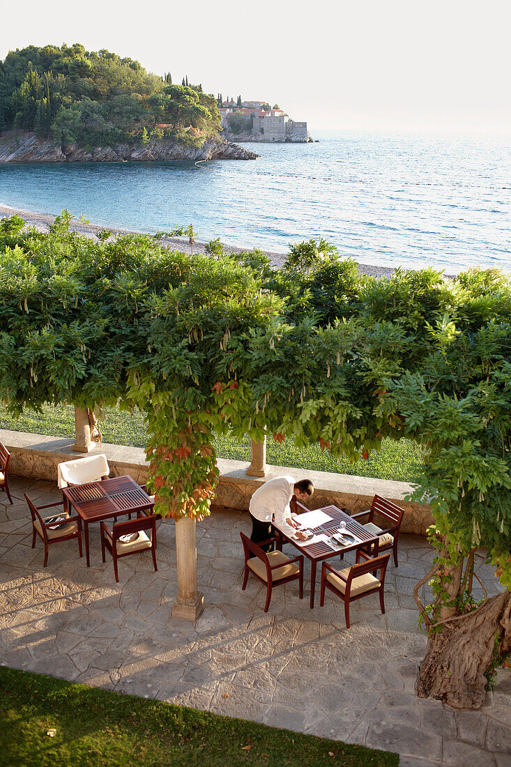 Waiter setting a table on terrace of Villa Milocer, Aman Sveti Stefan, Sveti Stefan, Budva, Montenegro