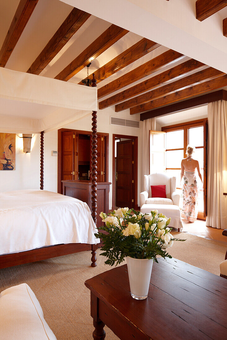 Frau in einer Hotelsuite mit Deckenbalken und Mobiliar im mallorquinischen Stil, Hotel La Residencia, Deia, Mallorca, Spanien