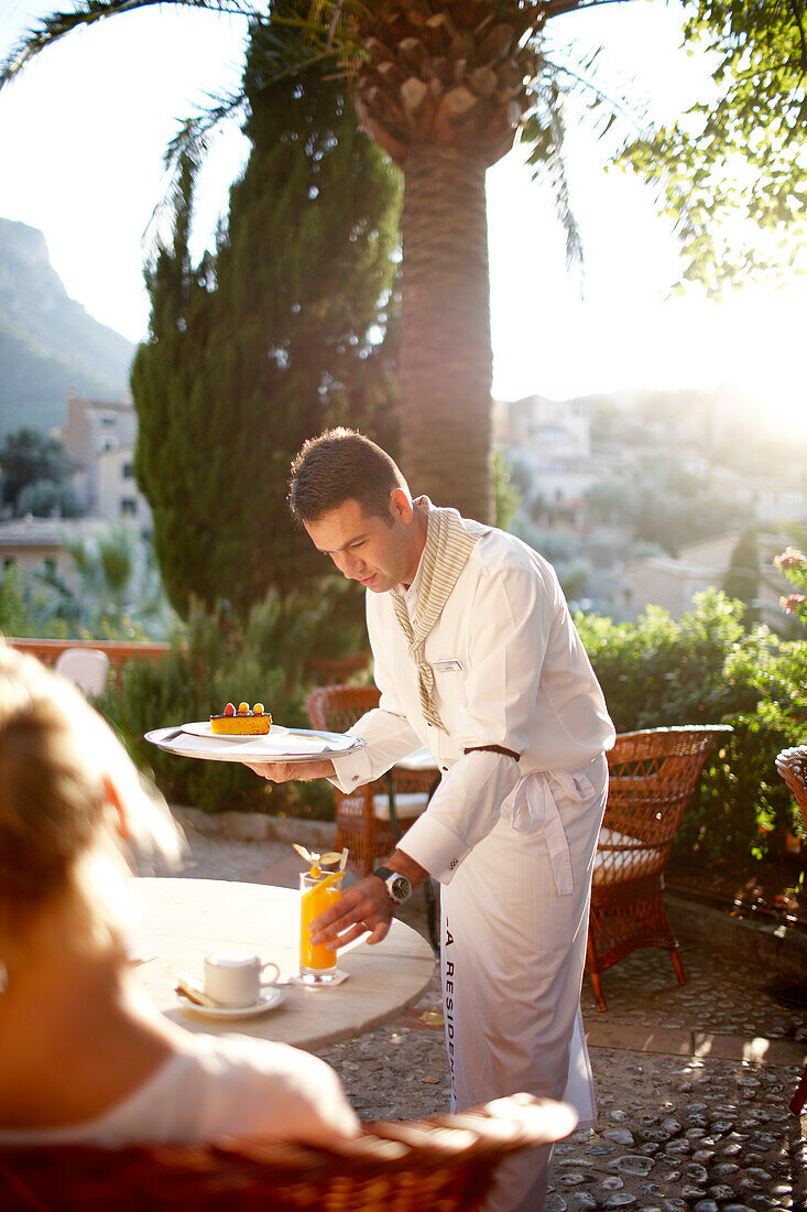 Kellner serviert eine Getränk auf der Terrasse des Bistro Son Moragues, Hotel La Residencia, Deia, Mallorca, Spanien