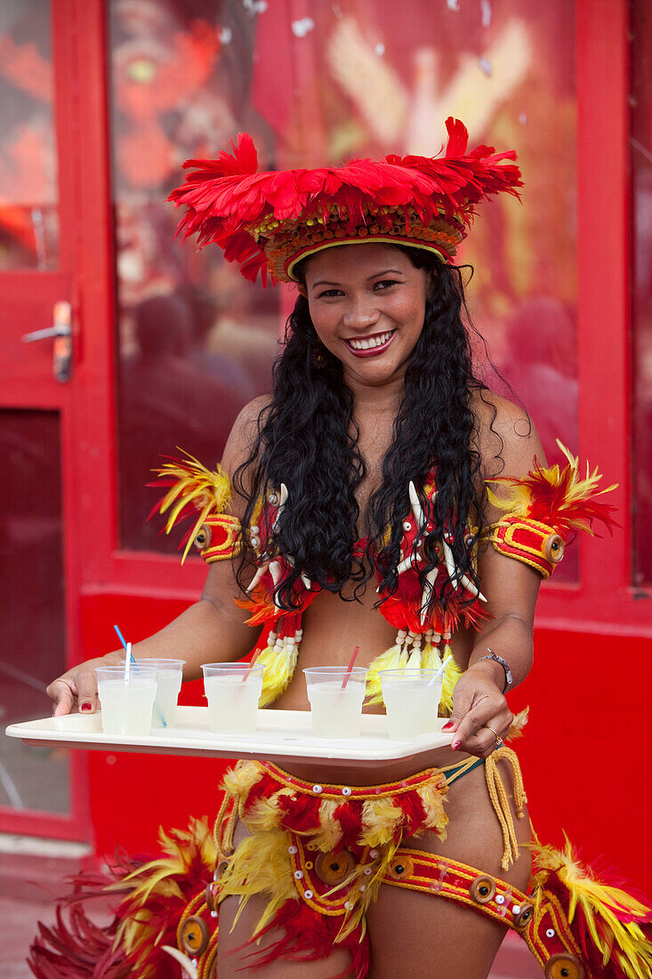 Cheerful woman serving drinks at Miscigenacao dance and folklore show with Boi Bumba festival costumes, Parintins, Amazonas, Brazil