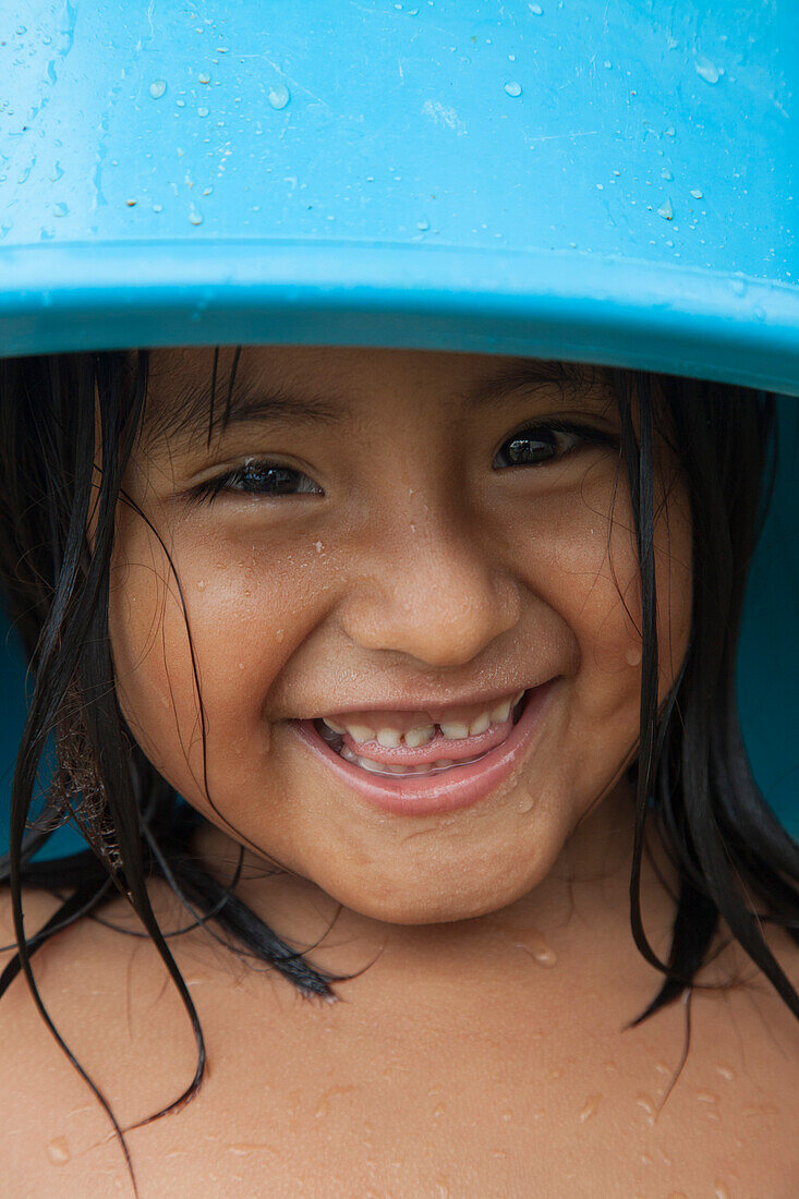 Young girl with blue bucket on her head at Agua Blanca village near Machalilla National Park, near Manta, Manabi, Ecuador