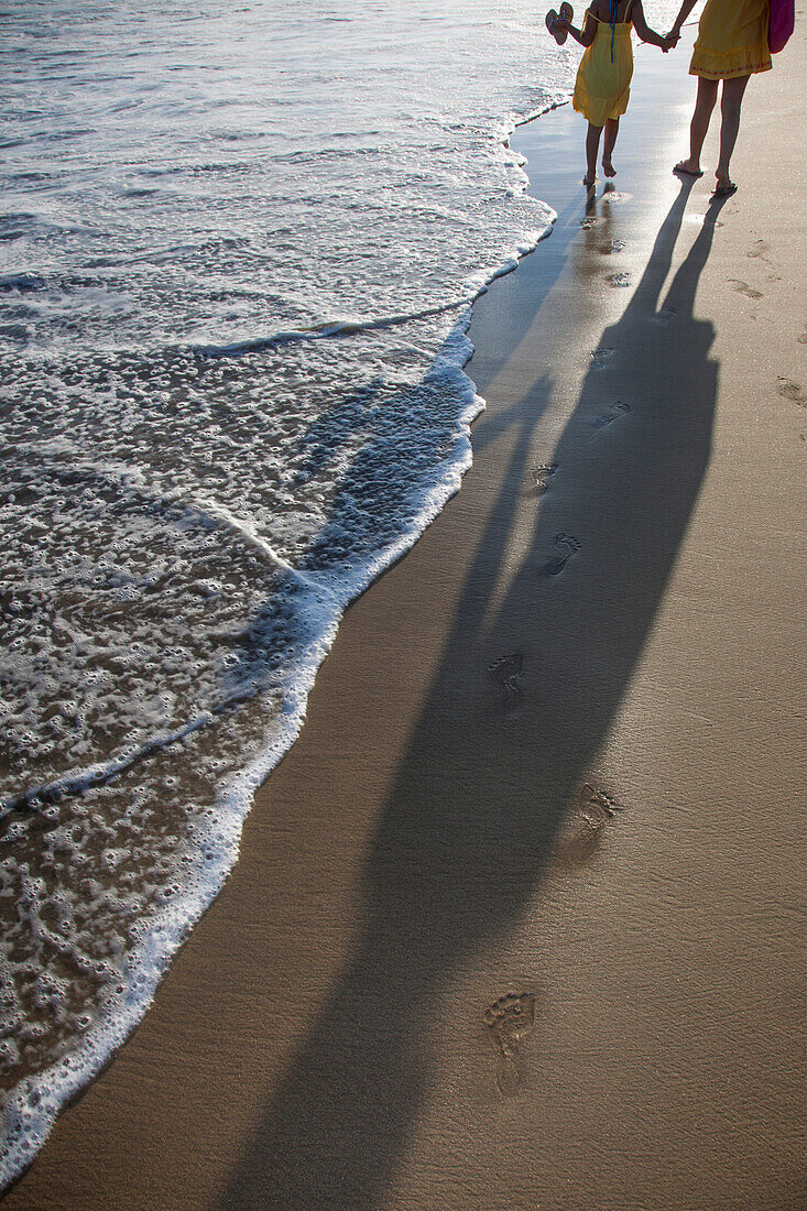 Mutter und Tochter mit langen Schatten spazieren am Strand Playa Las Hamacas Acapulco, Guerrero, Mexiko, Mittelamerika