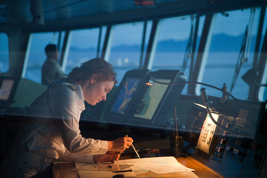 Safety Officer Claudia Kempkes charting course on bridge of cruise ship MS Deutschland (Reederei Peter Deilmann) at dawn, Puerto Vallarta, Jalisco, Mexico