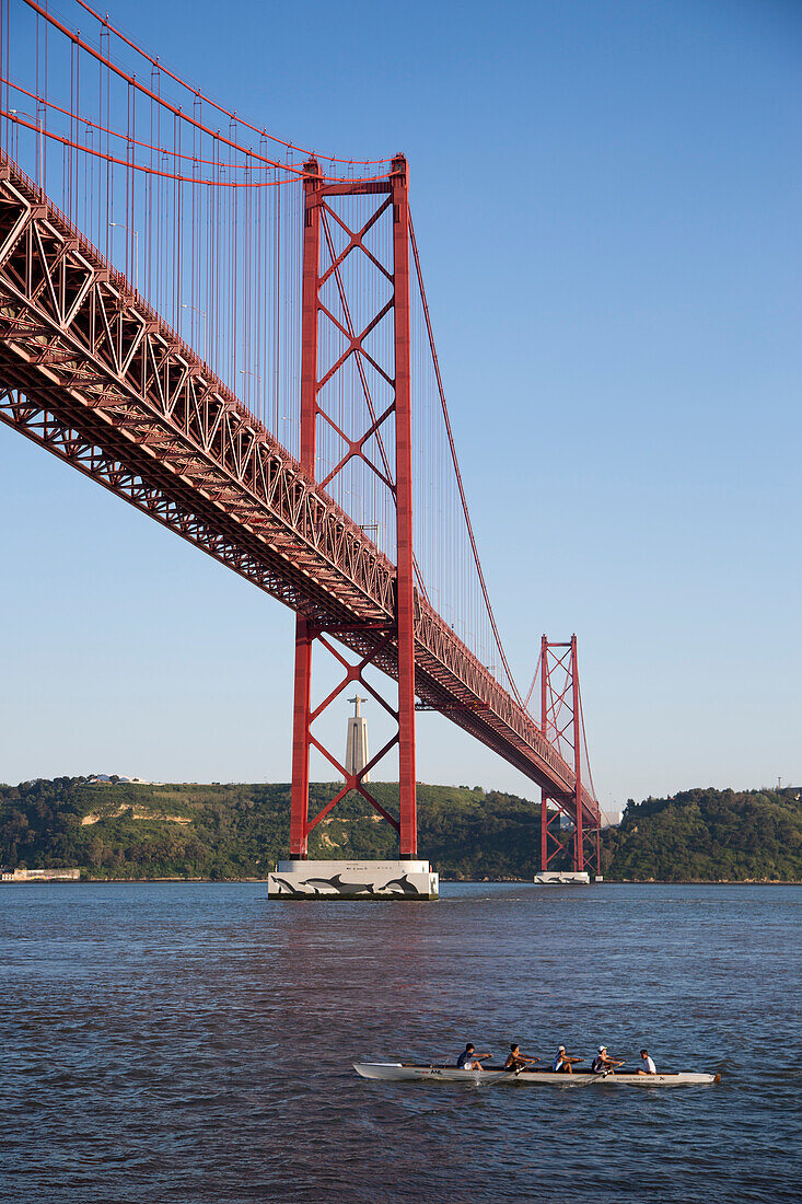 Kayakers paddling under Ponte 25 de Abril bridge over Tagus river with Cristo Rei statue in the background, Lisbon, Lisboa, Portugal