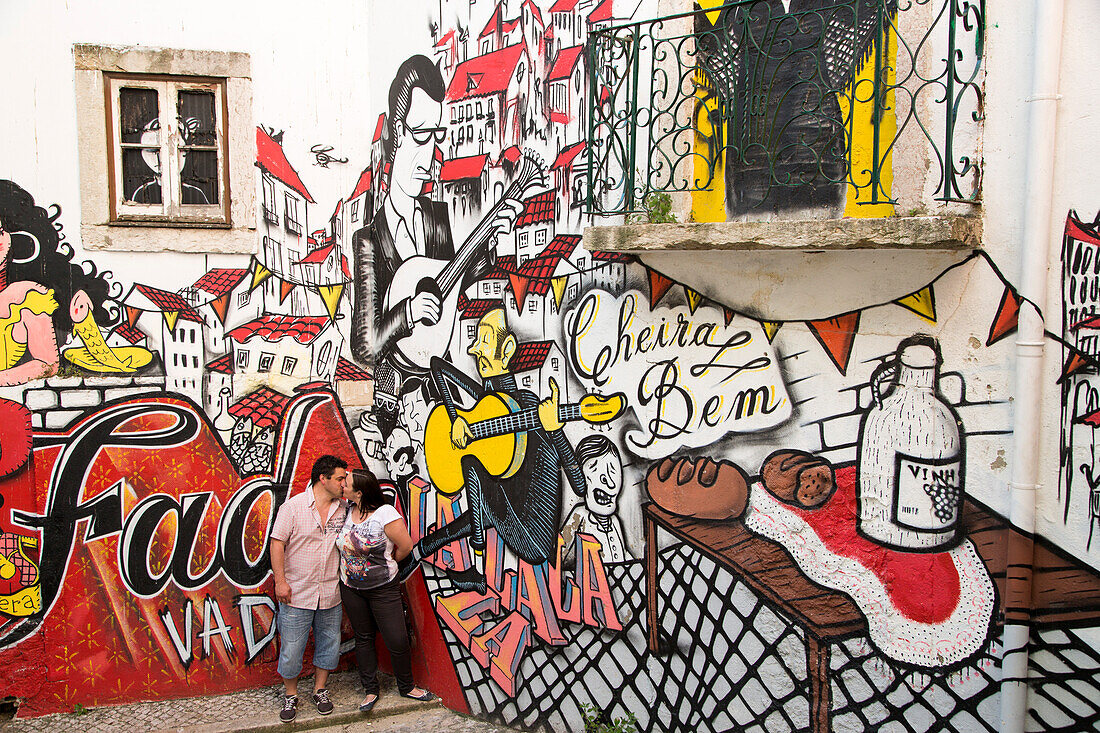 Couple kissing in front of a graffiti mural on the wall of steps linking the Baixa and Alfama district, Lisbon, Lisboa, Portugal