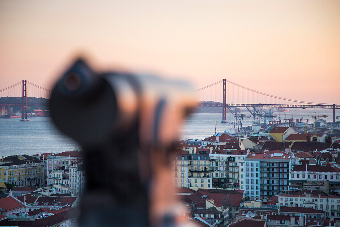 Coin-operated telescope at Castelo de San Jorge, St. George's Castle, in the Alfama district with view over the city and Ponte 25 de Abril bridge over Tagus river at sunset, Lisbon, Lisboa, Portugal