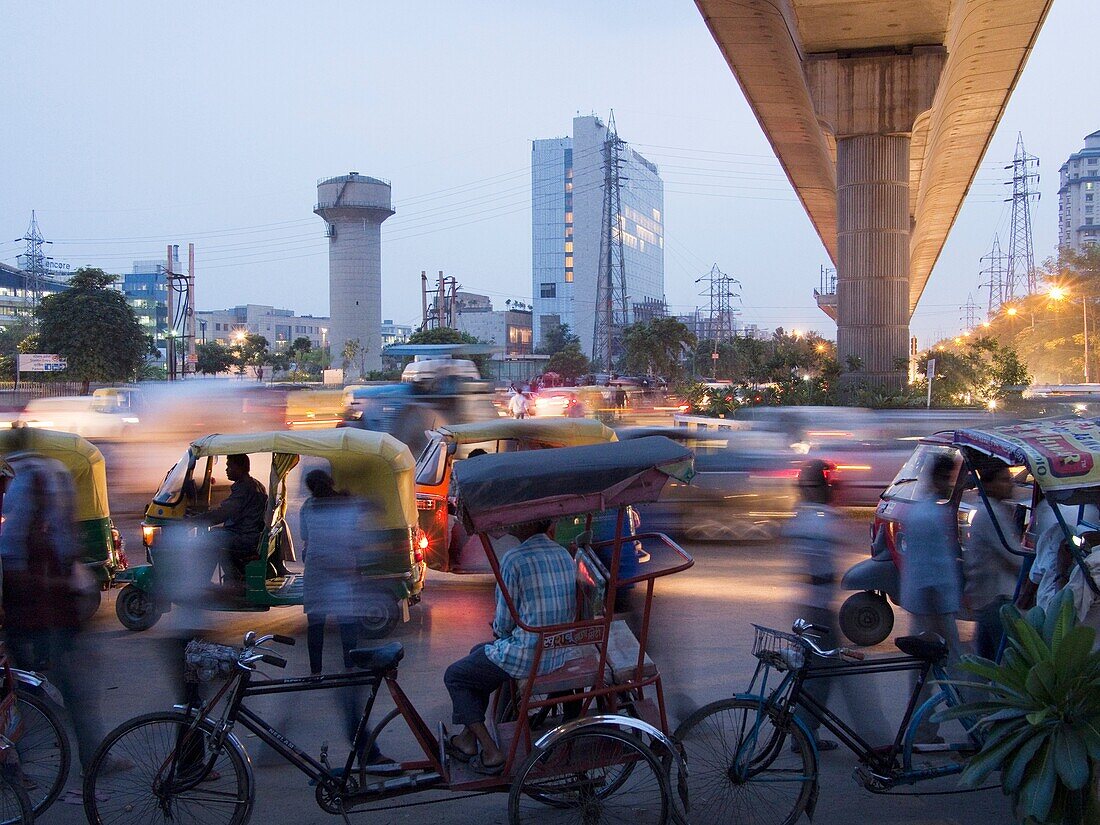 Commuters and bicycle rickshaw drivers swarm the Gurgaon Metro station south of Delhi, India