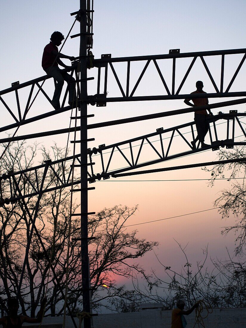 Silhouette of man working on metal frame during sunset, Mysore, India