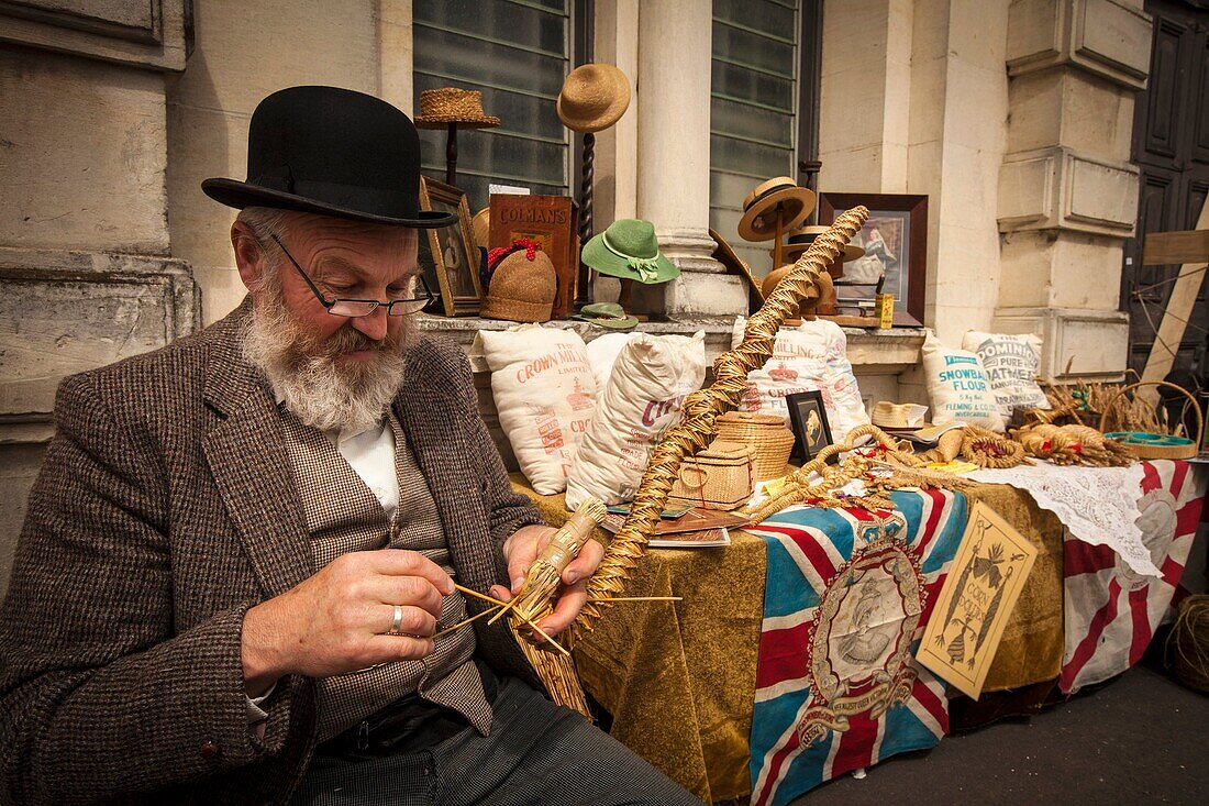 Man making walking stick, corn stalk weaving and plaiting, ancient craft, Victorian festival, historic precinct, Oamaru, Otago