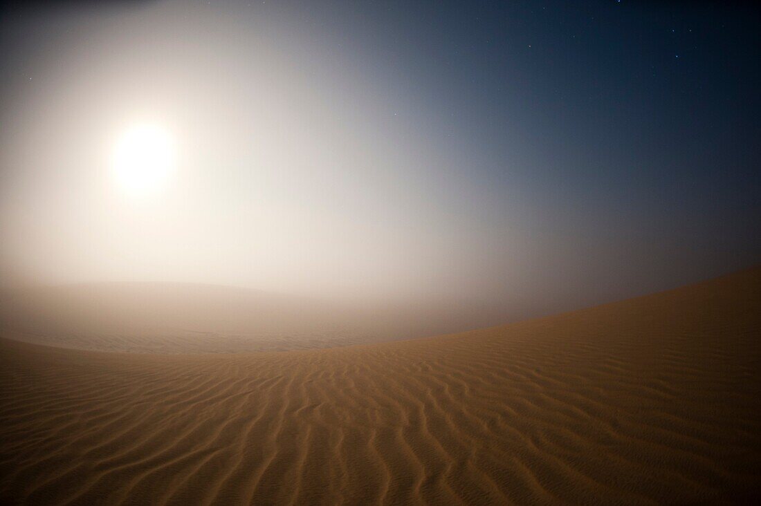 Moonrise in the mist over Sand Dunes, Skeleton Coast National Park, Namibia.