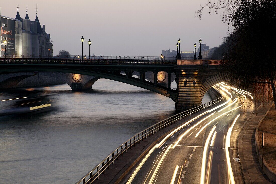 The twilight view of riverside traffics and Pont au Change over River Seine in background  Paris  France.