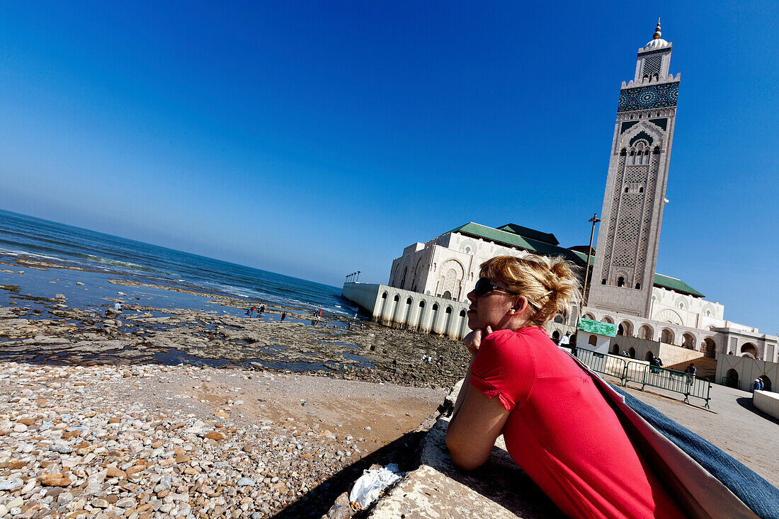 Woman stares out at the Atlantic Ocean near the Hassan II Mosque in the Kenzi Towers, Casablanca, Morocco